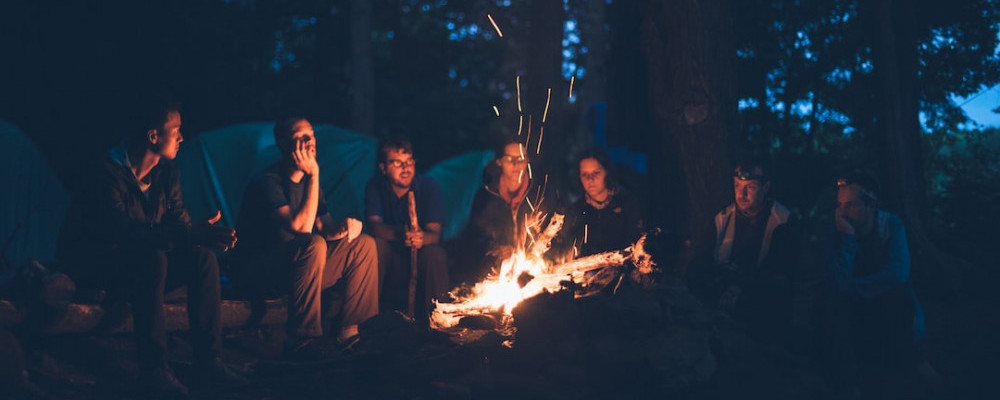 Seven friends sitting outside around the fire that they created in their outdoor wood fire pit. Outdoor Wood Fire Pits