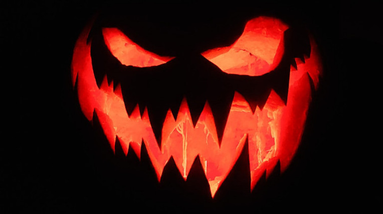 Scary jack o lantern with candle inside smiling creepily.