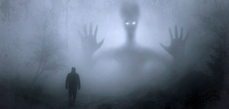 Man walking in the fog towards a giant alien. 