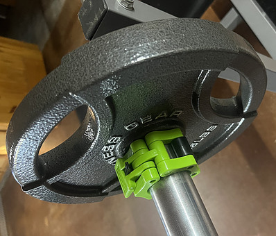 Green clamp on barbell keeping the weights safe and secure from falling off.