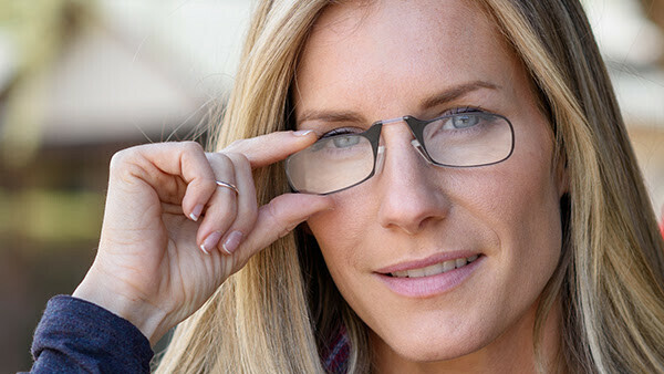 Woman holding up a pair of ThinOptics Glasses to her eyes.
